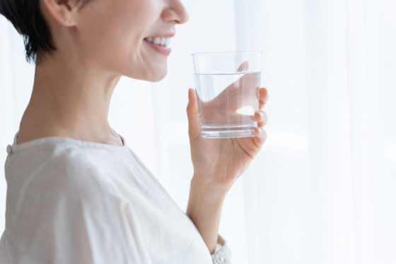 水のはいったコップをもつ女性